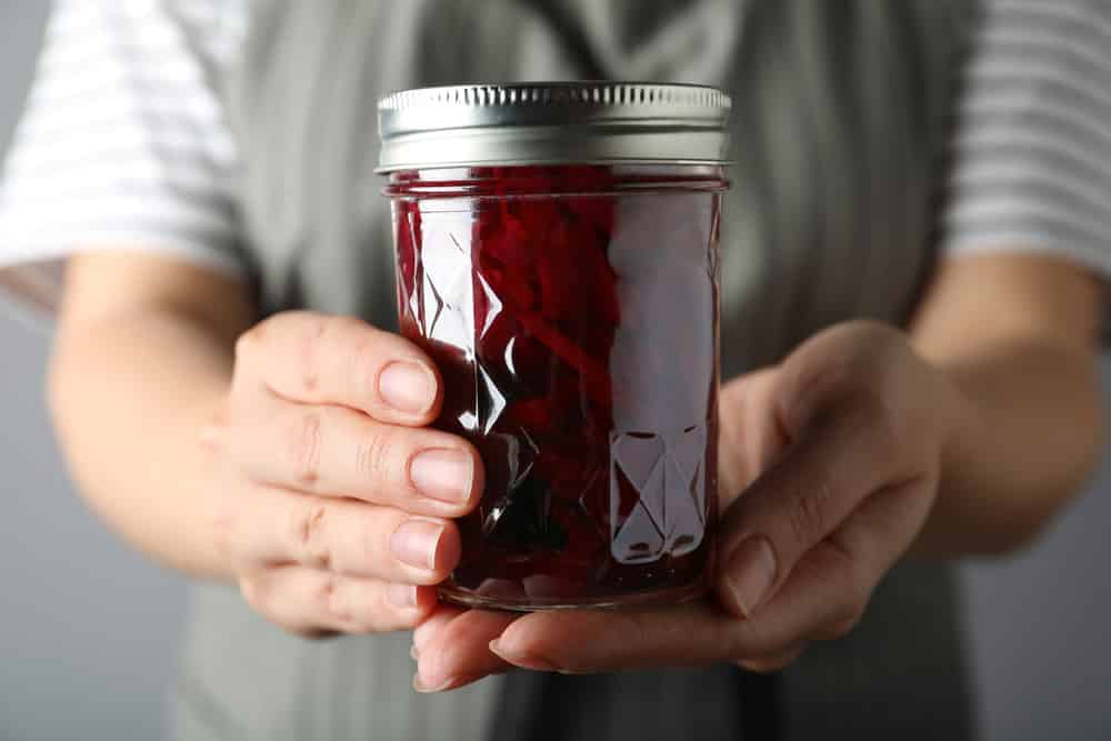 Woman holding glass jar with pickled beets