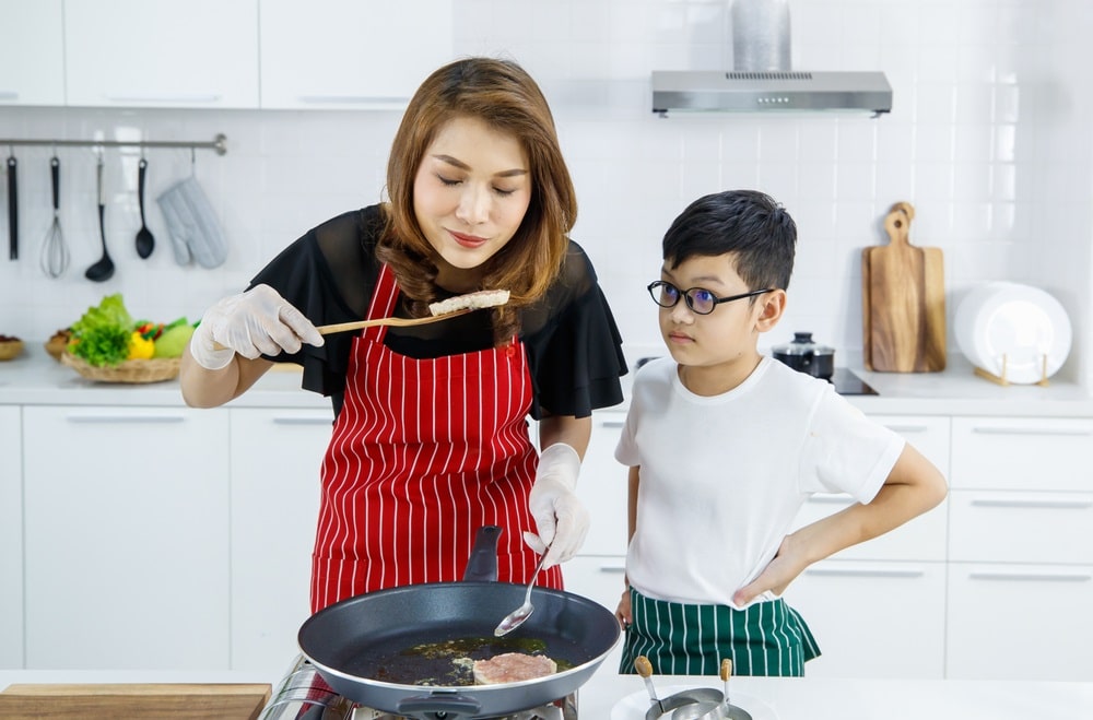 mother and son frying burger patties