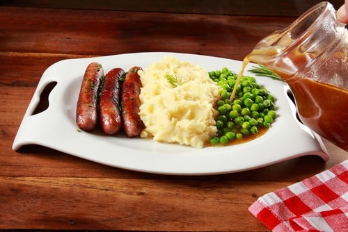 Delicious gravy on Sausage bangers, mashed potatoes and peas