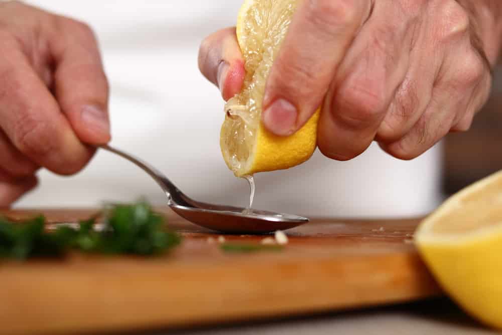 Chef squeezing lemon juice into spoon