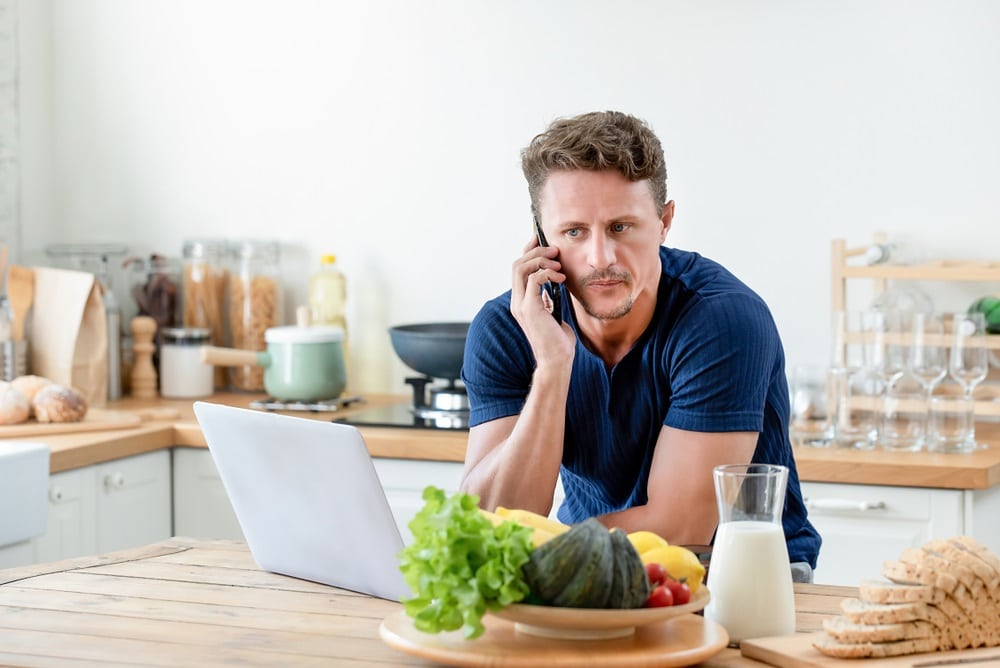 Casual man calling on cell phone in kitchen