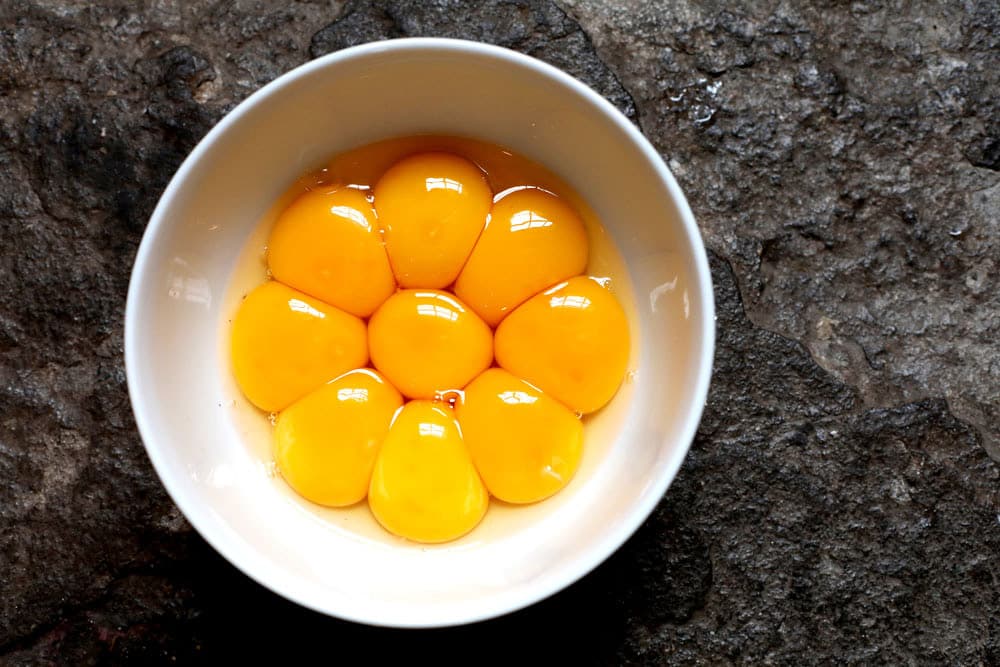 Bright yellow egg yolks in a white bowl 