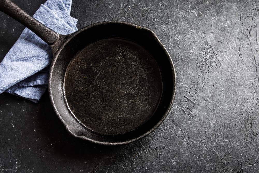 Cast iron pan on rustic black stone background