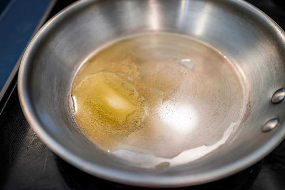 Grass-fed butter melting in stainless steel frying pan