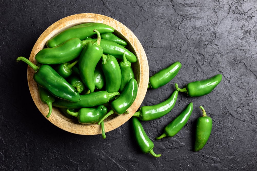 Green jalapeno hot pepper in wooden plate closeup