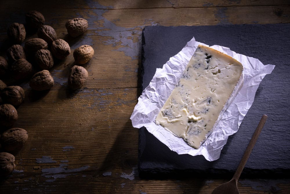 slice of Gorgonzola cheese on black cutting board