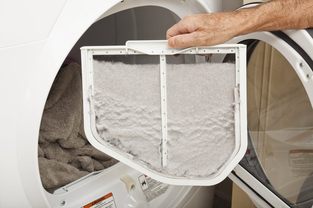 Hand holding a clothes dryer lint filter that is covered with lint