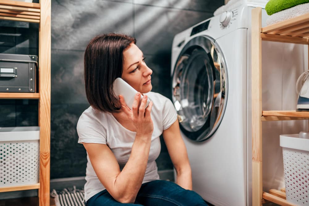 Woman wearing white shirt sitting at laundry room