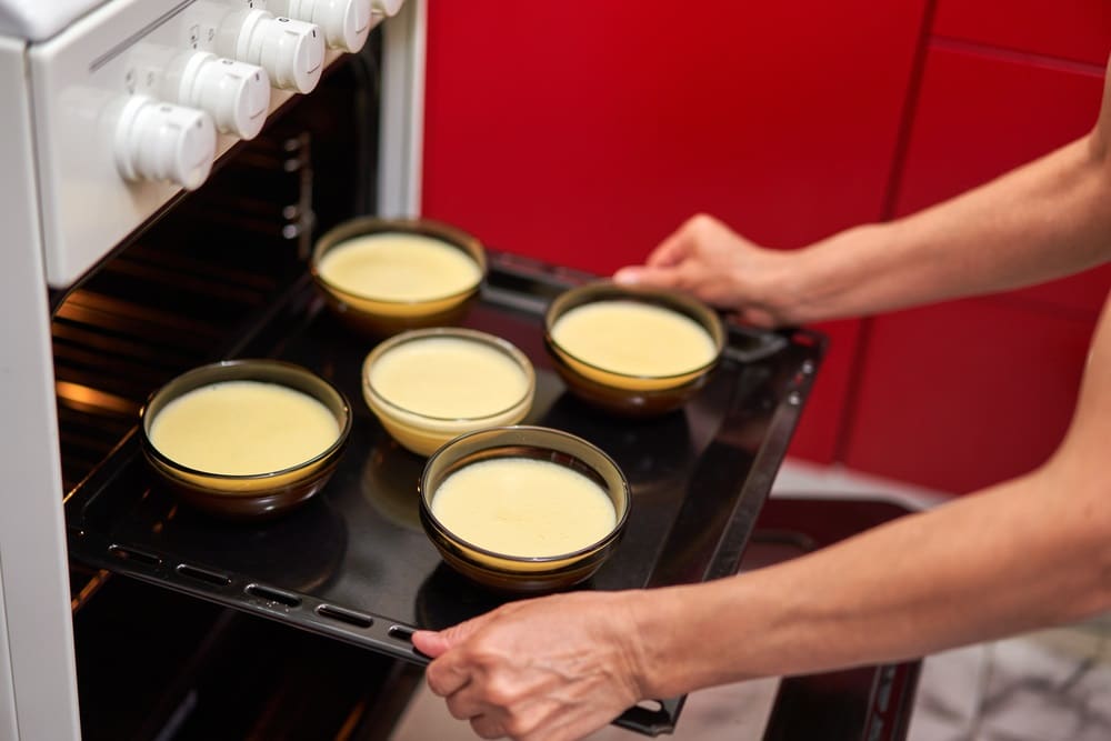 Inserting tray with creme brulee bowls into the oven