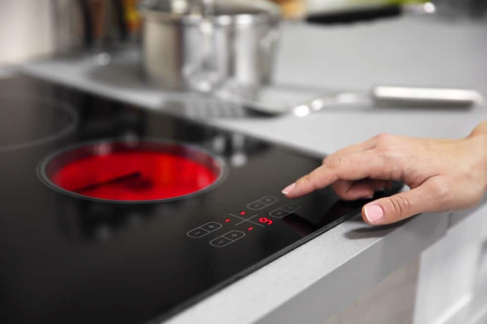 hand turns on electric hob