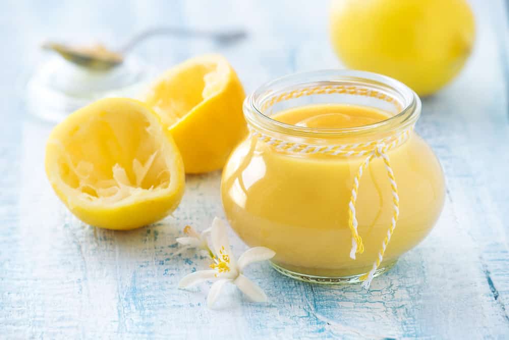 Lemon curd or custard in a jar with squeezed lemons