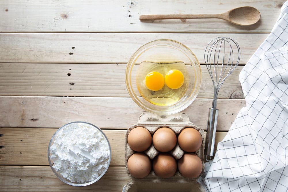 Raw eggs in a bowl with cornstarch on the table