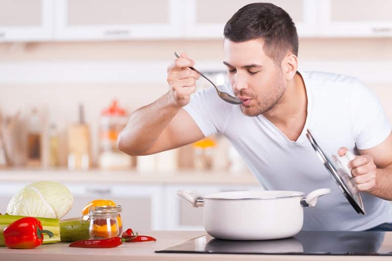 man tasting soup from pot