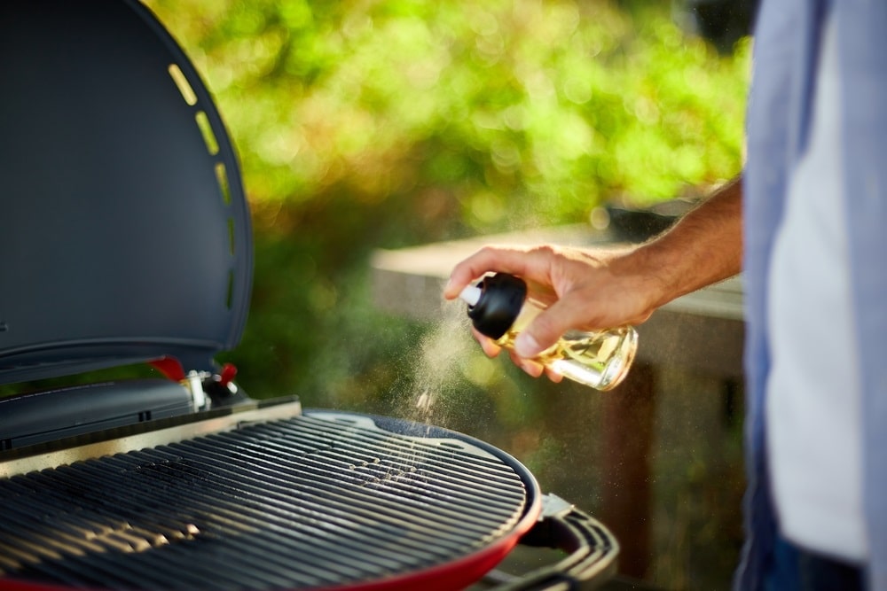 spraying oil on barbecue gas grill