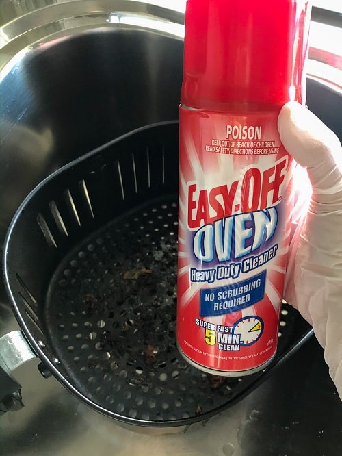 hand holding a spray of Easy Off to clean an air fryer