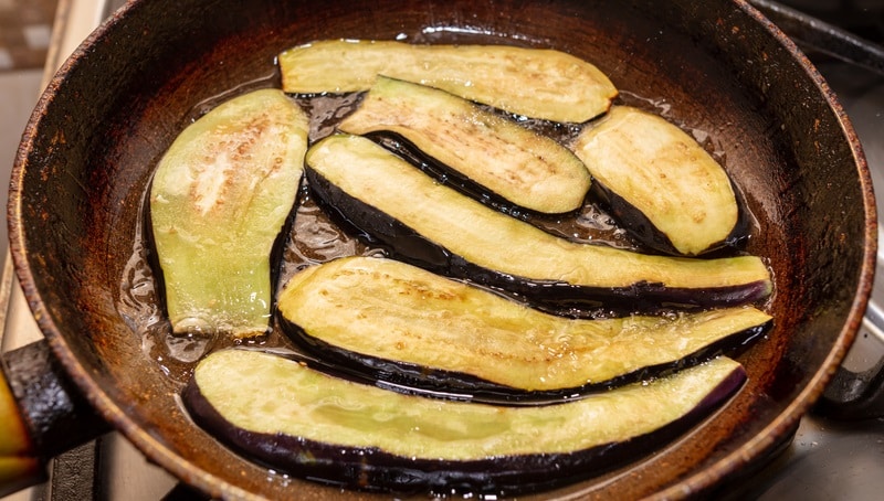 Eggplants are fried in oil in a pan