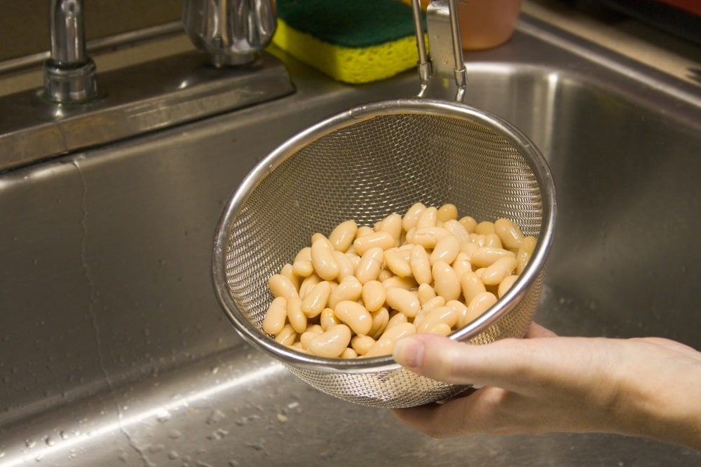 Rinsed cannellini beans held in a strainer 