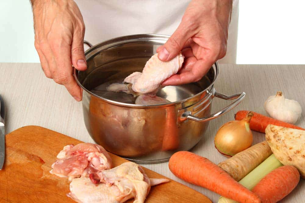 Adding raw chicken into the pot.
