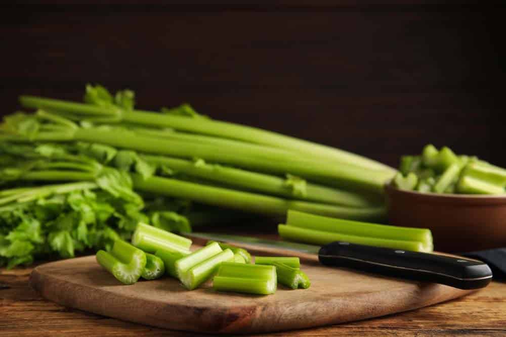 Cut fresh green celery on wooden board.