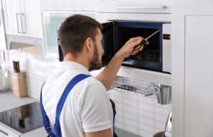 Man repairing microwave in kitchen