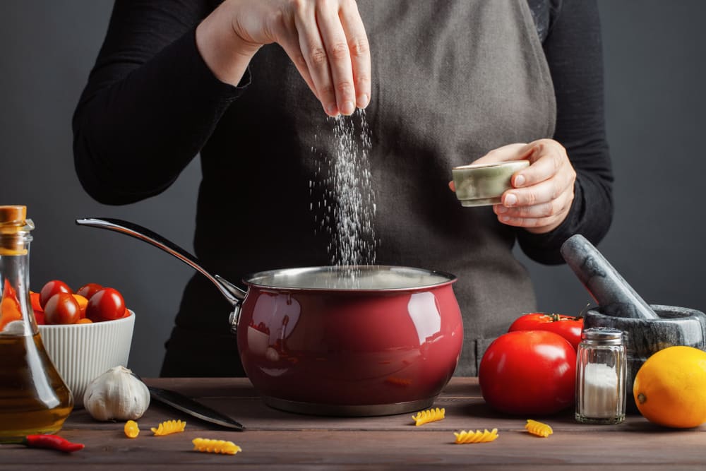 A woman seasoning a food in a pot