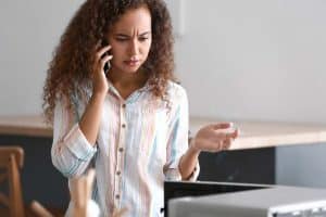 Woman talking by mobile phone near damaged microwave