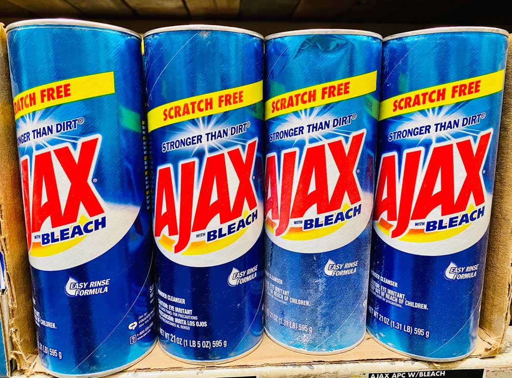 Cans of Ajax with bleach powder in a box on a shelf