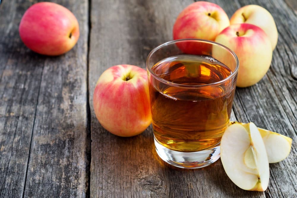 apple juice in a glass and apples on wooden 