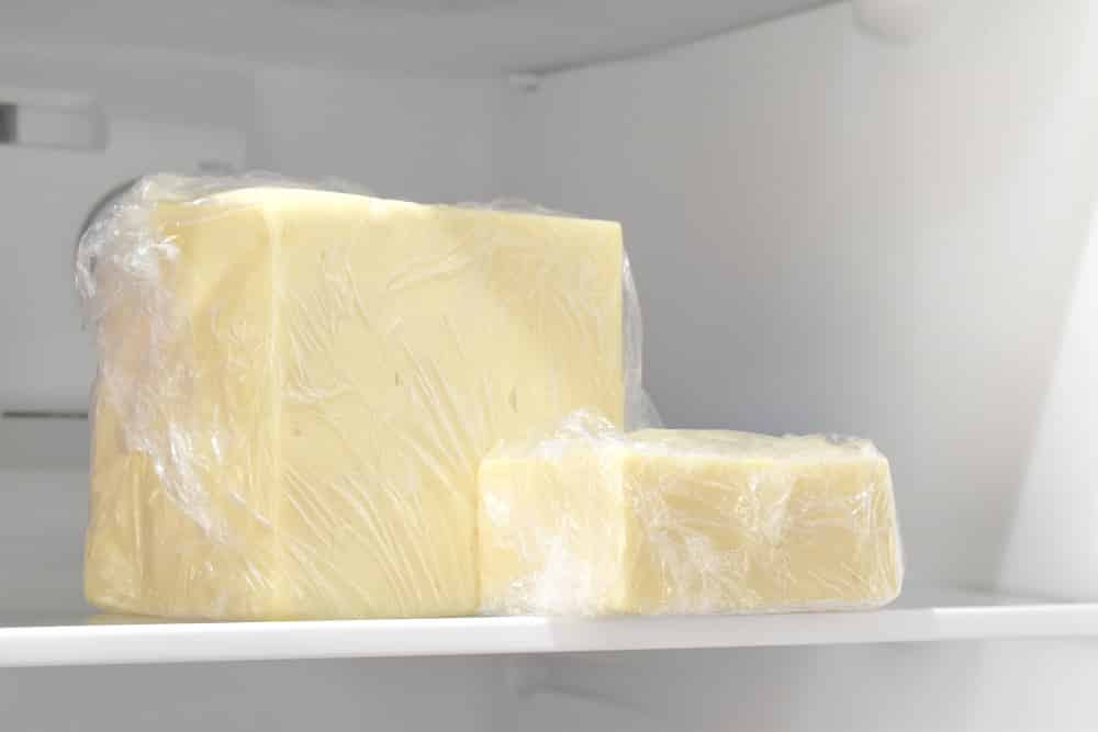 Cheese in plastic wrap in the fridge.