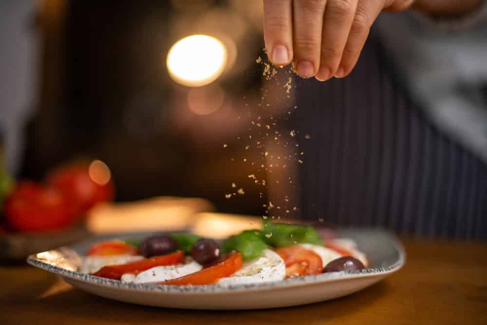 Close up of female chef hands seasoning a plate