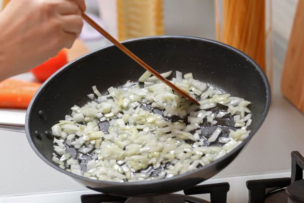 Woman fry onions in a hot pan