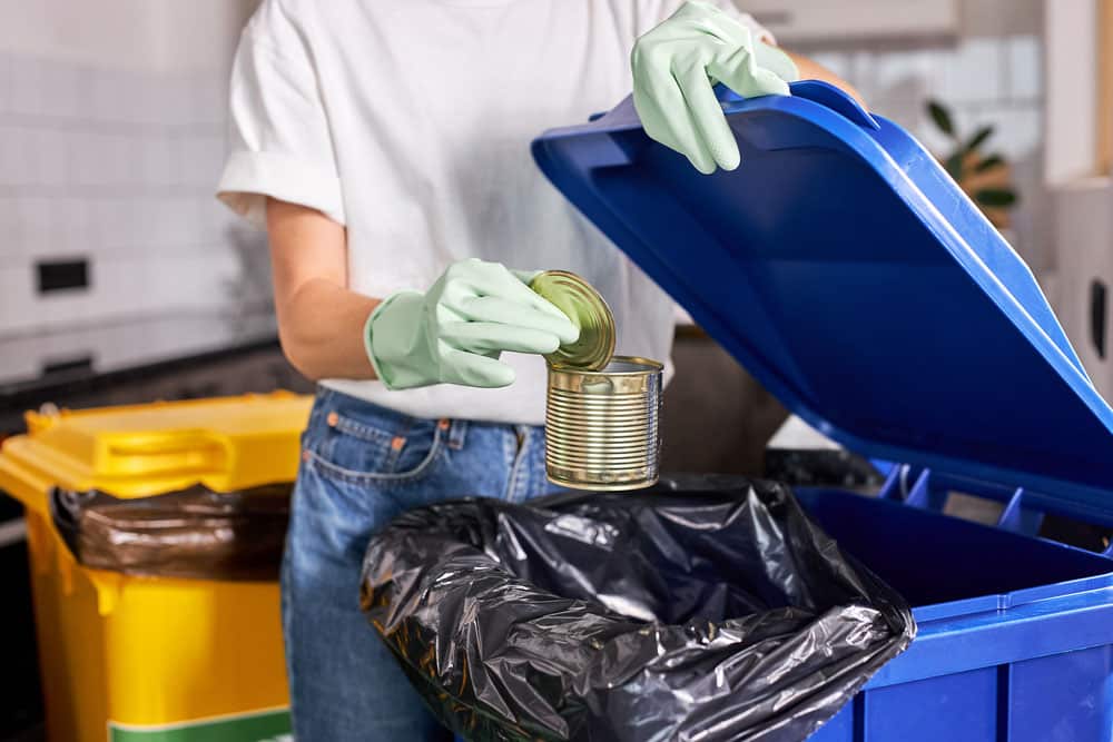 cropped female throw the tin can in trash can