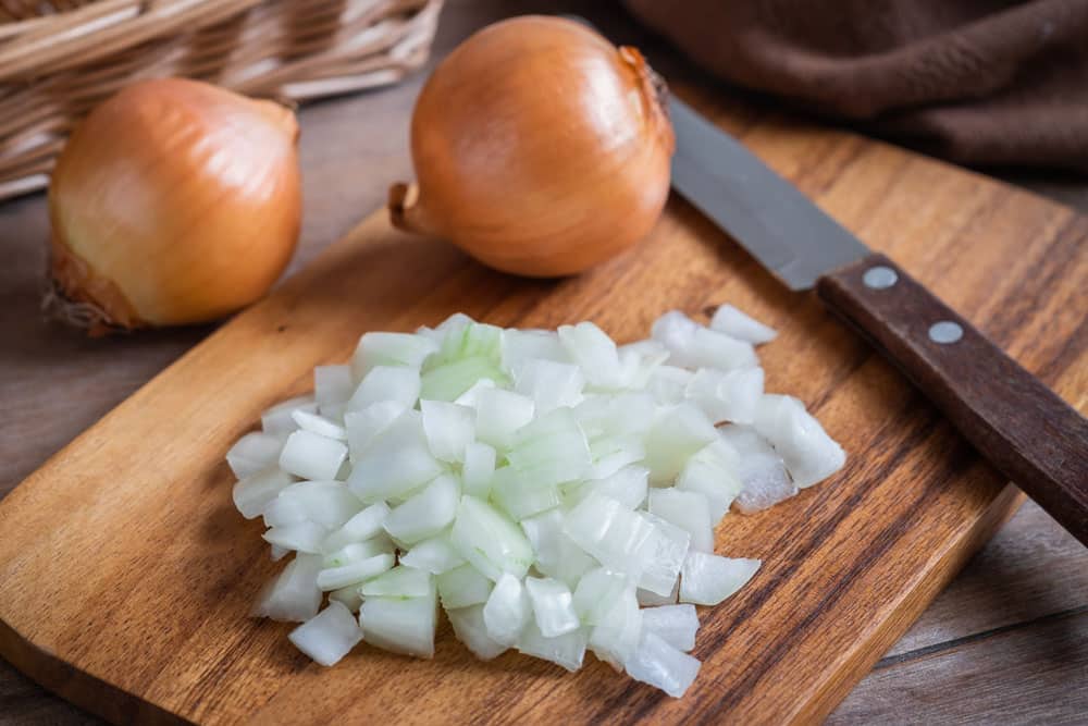 Fresh chopped onions on wooden cutting board