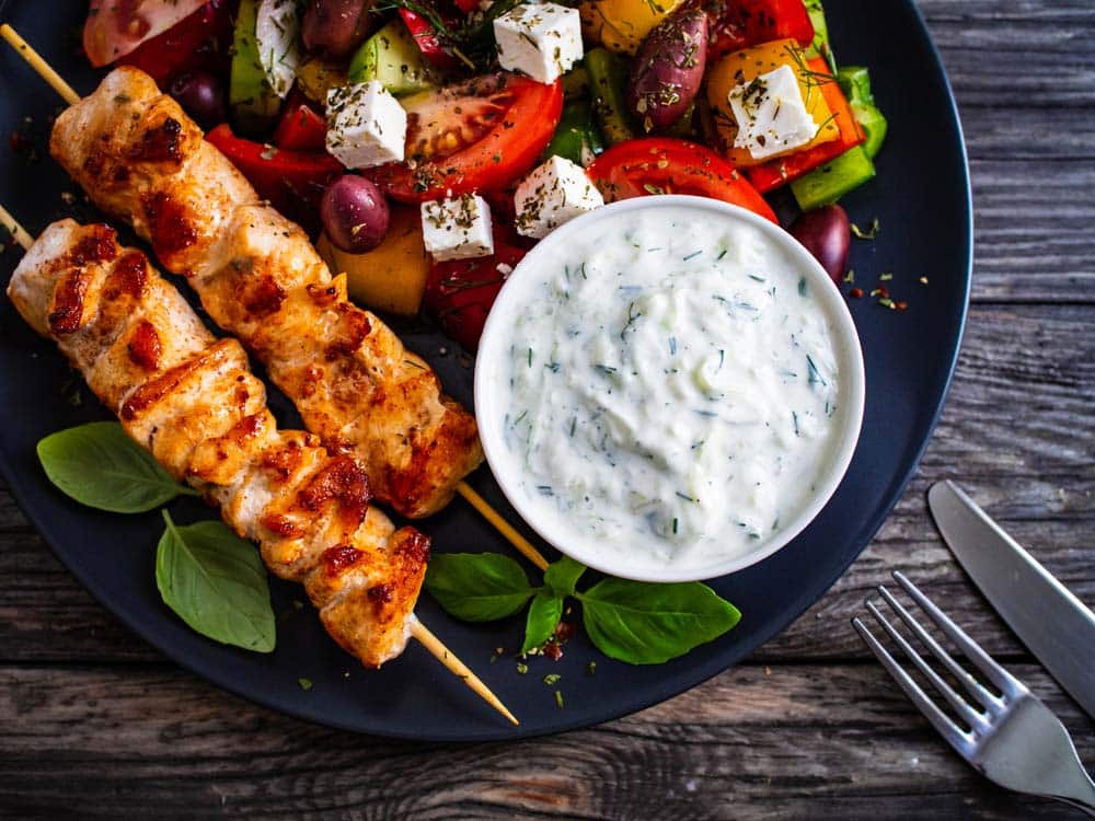 Fried souvlaki, greek salad and tzatziki on wooden table