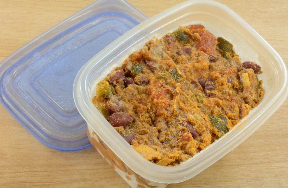 Frozen beef chili leftovers thawing in plastic storage container