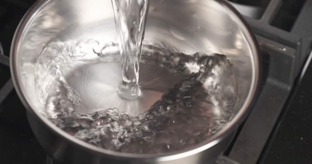 Handheld shot of pouring water into saucepan