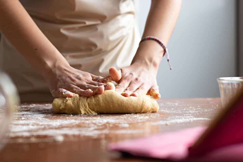 Hands of a young woman kneading dough
