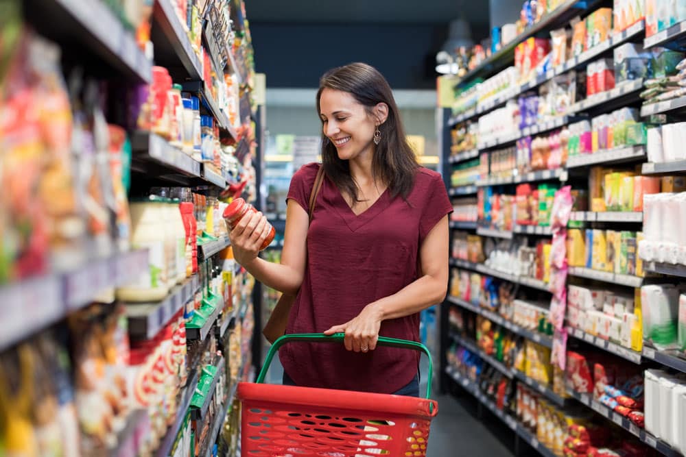 Happy mature woman looking at product at grocery store