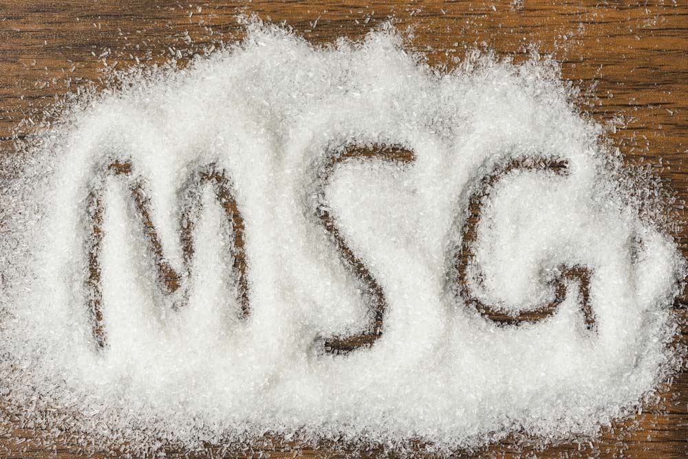 Heap of monosodium glutamate on wooden with text MSG
