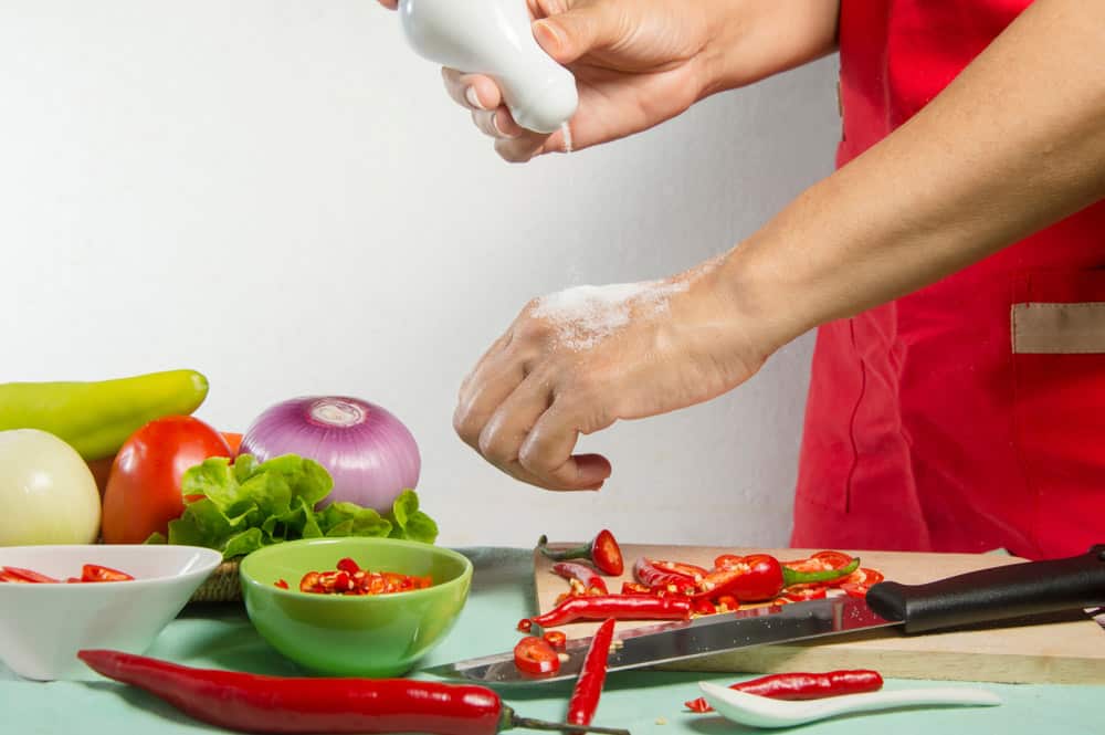 a housewife is sprinkling salt on her wet hand to stop hot pepper burn