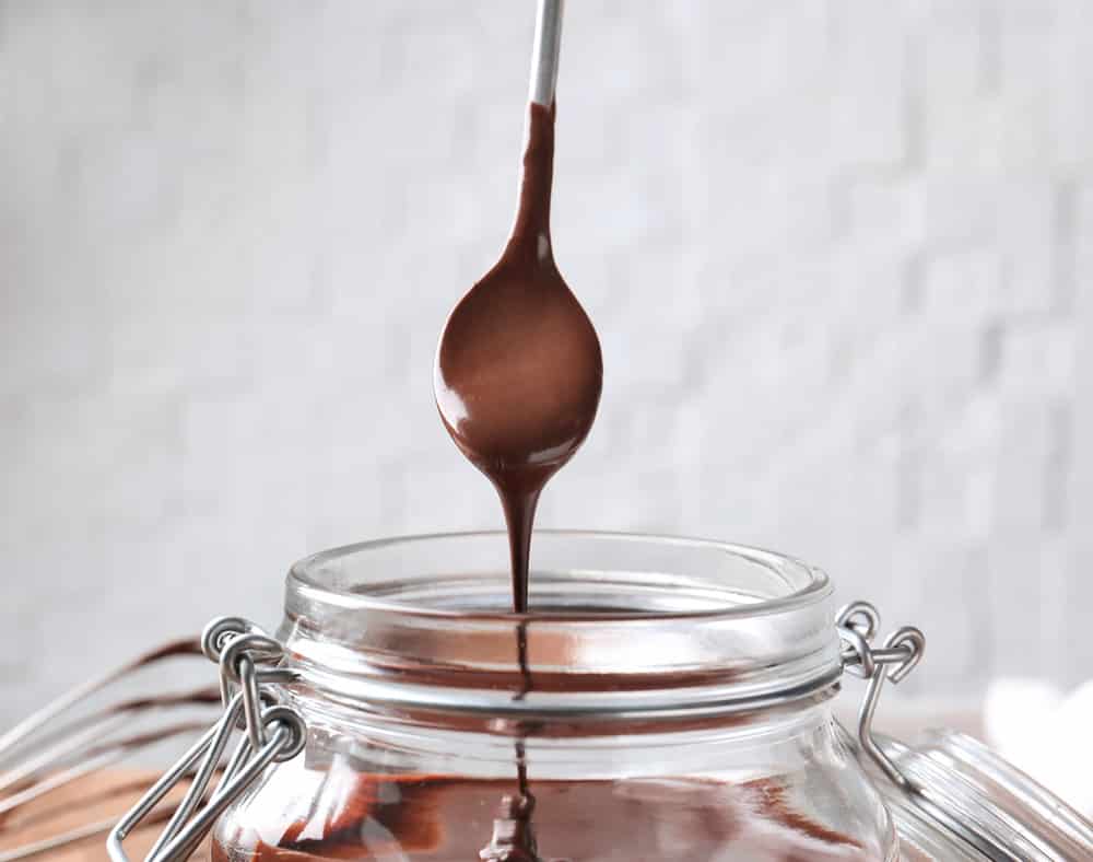 Jar with delicious chocolate sauce and spoon