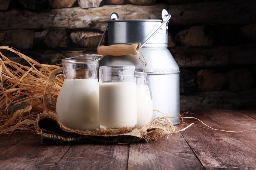 A jug of milk and glass of milk on a wooden table