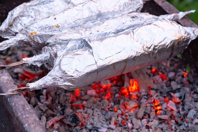 juicy fresh slices pork strung metal skewers wrapped aluminum foil grilled