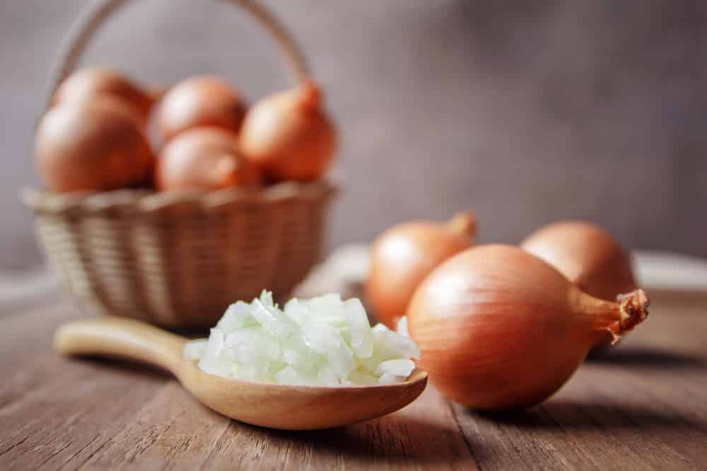 Onion and slices in wood spoon for cooking.