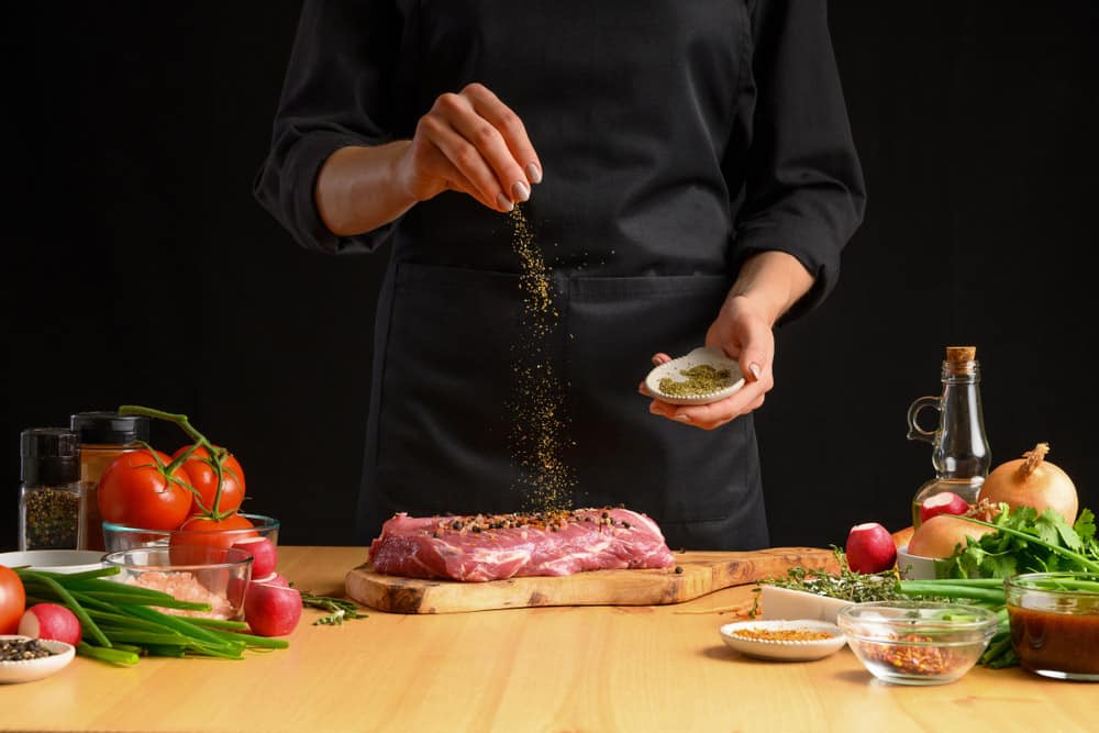 Pork steak and green herbs from the chef in the background