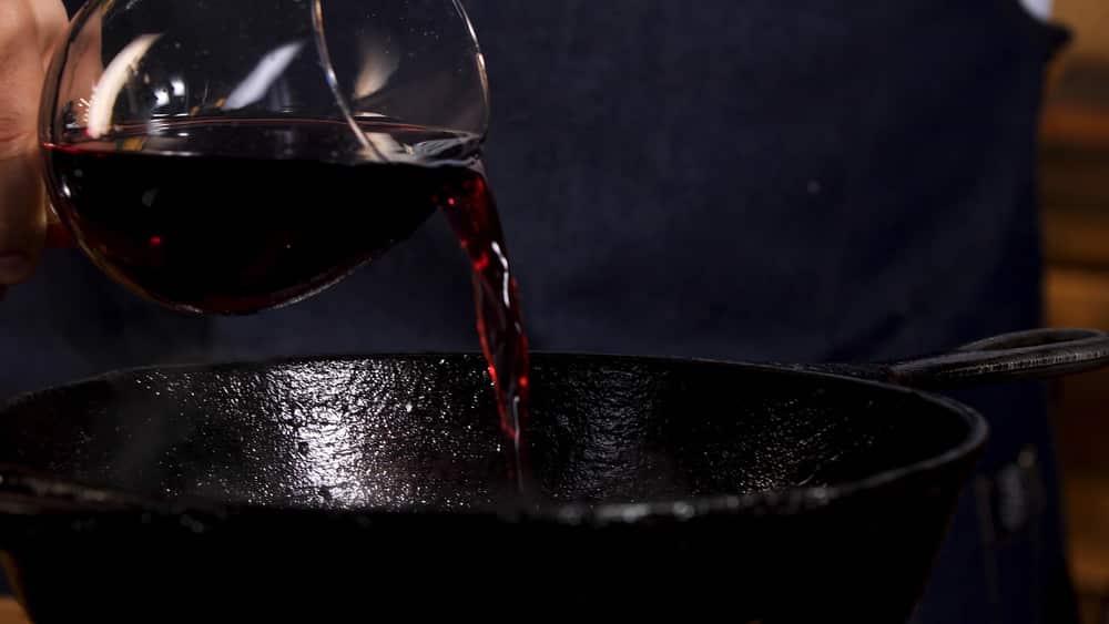 Pouring red wine into frying pan.