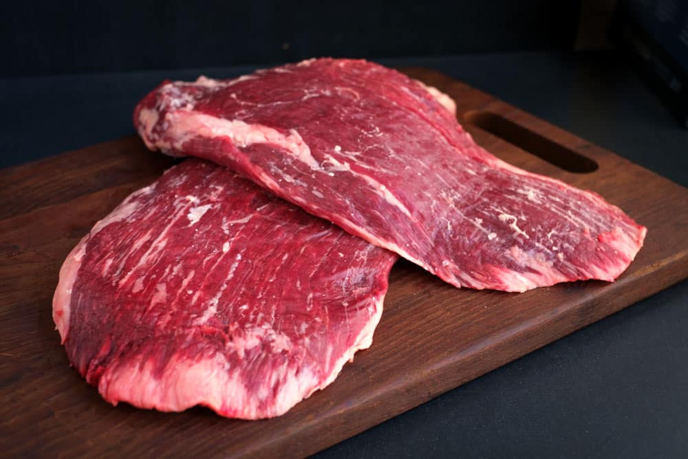 raw flank beef on a wooden Board