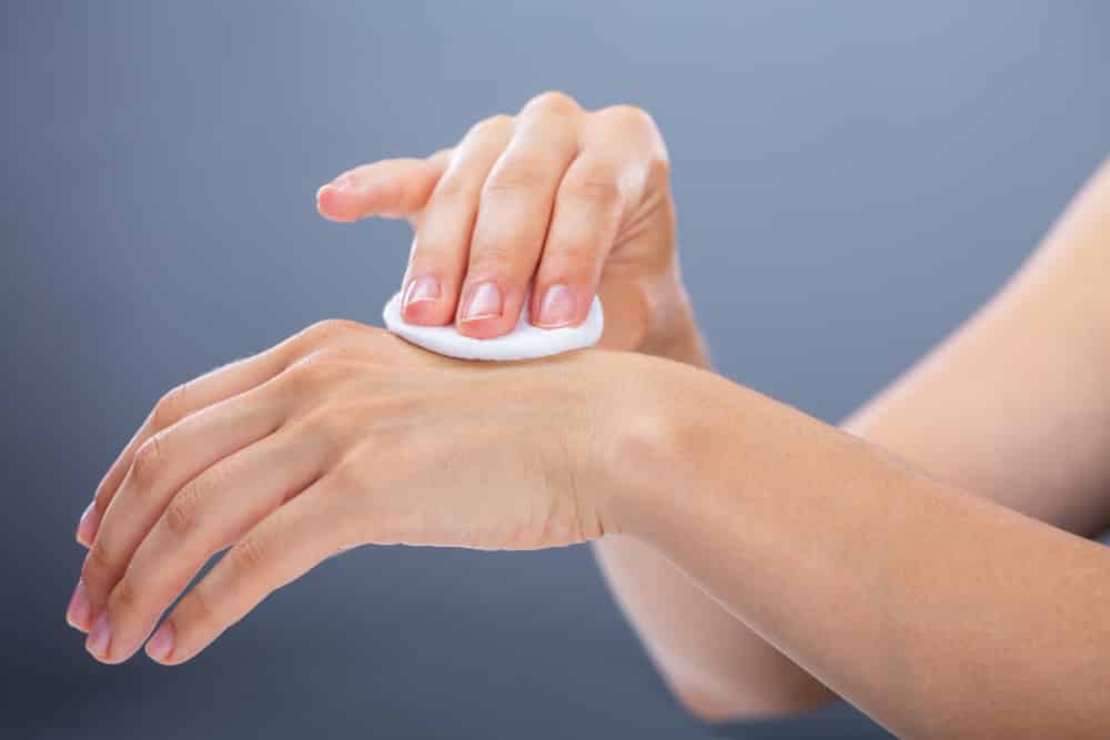 Woman Cleaning Her Hand With Cotton Pad