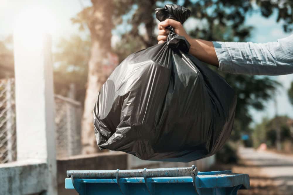 woman hand holding garbage black bag put in to trash