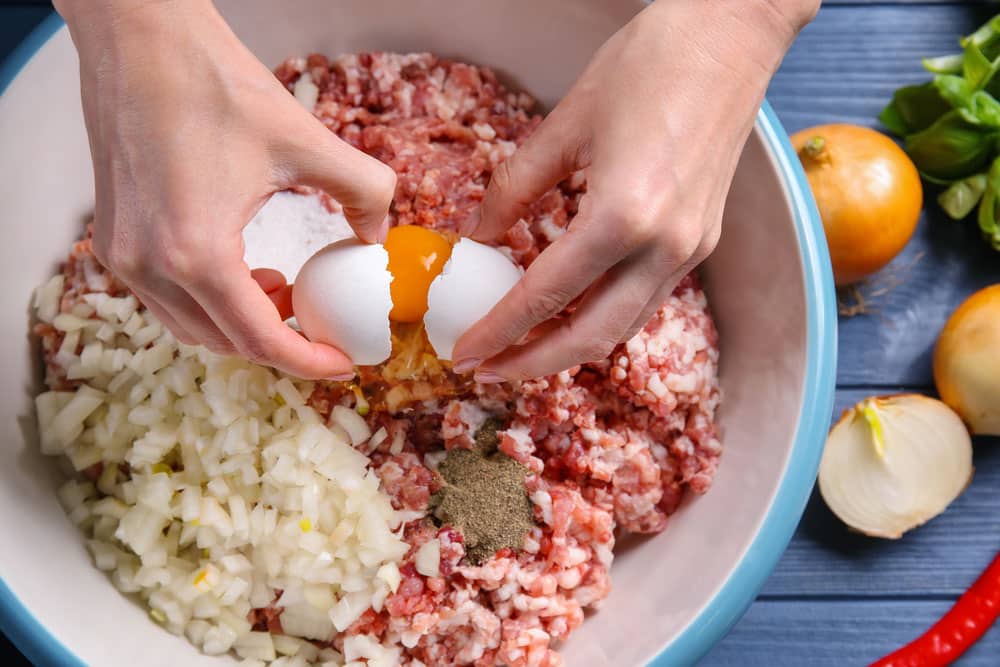 Woman preparing delicious turkey meatloaf in bowl